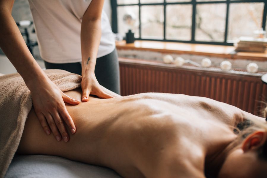 Therapist applying firm forearm pressure along a guest’s back